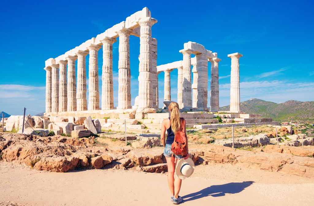 women in Athens standing in front of ruins