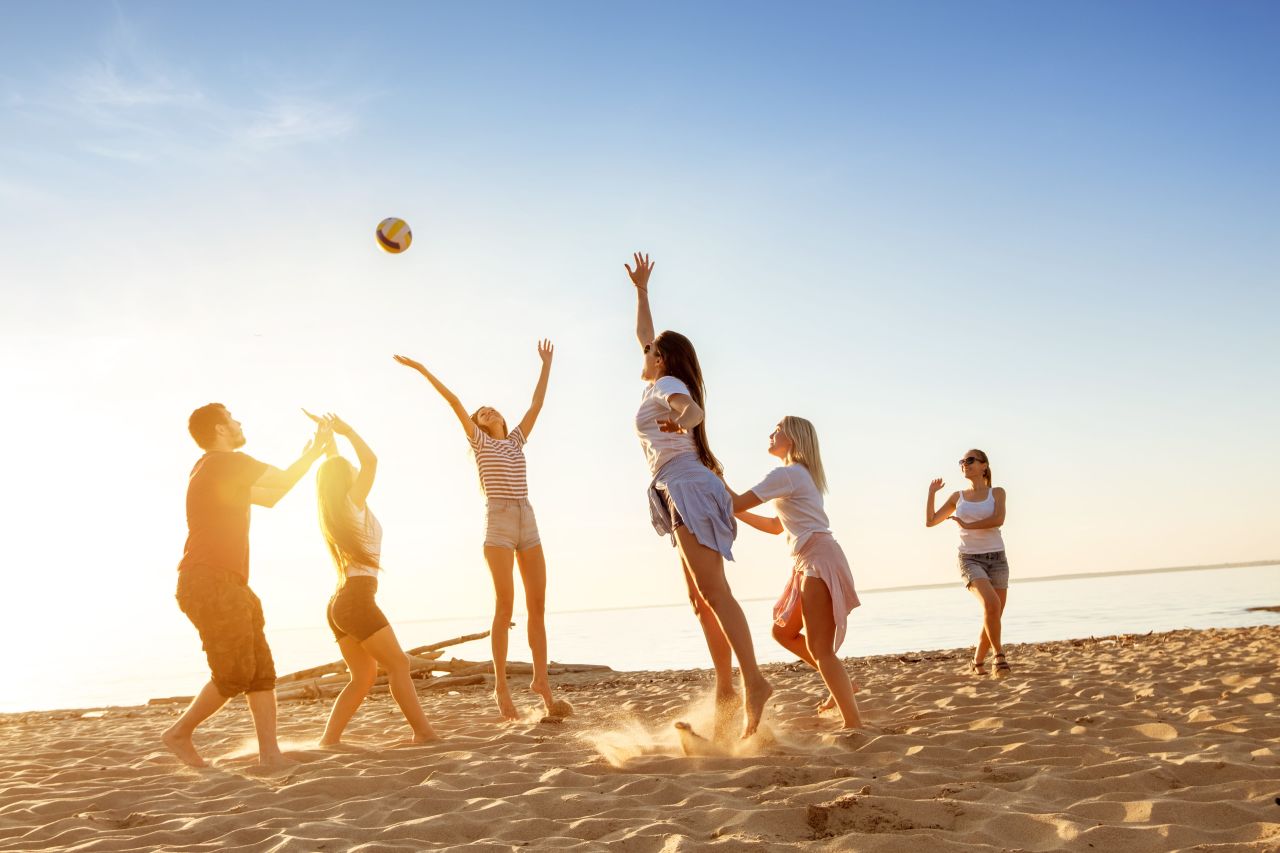 A group playing volleyball on the beach whilst on holiday