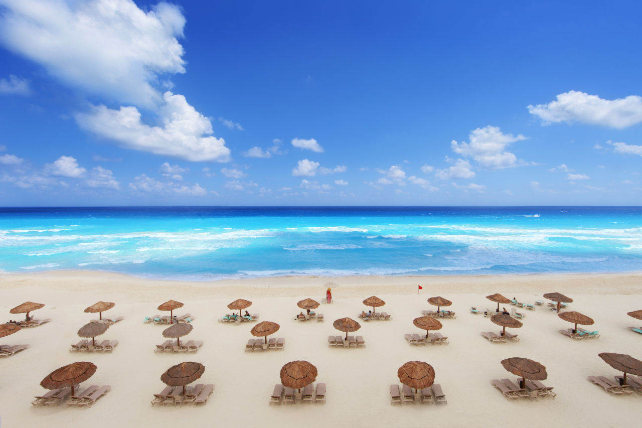 Sunbeds and umbrellas lining an idyllic beach in Cancun