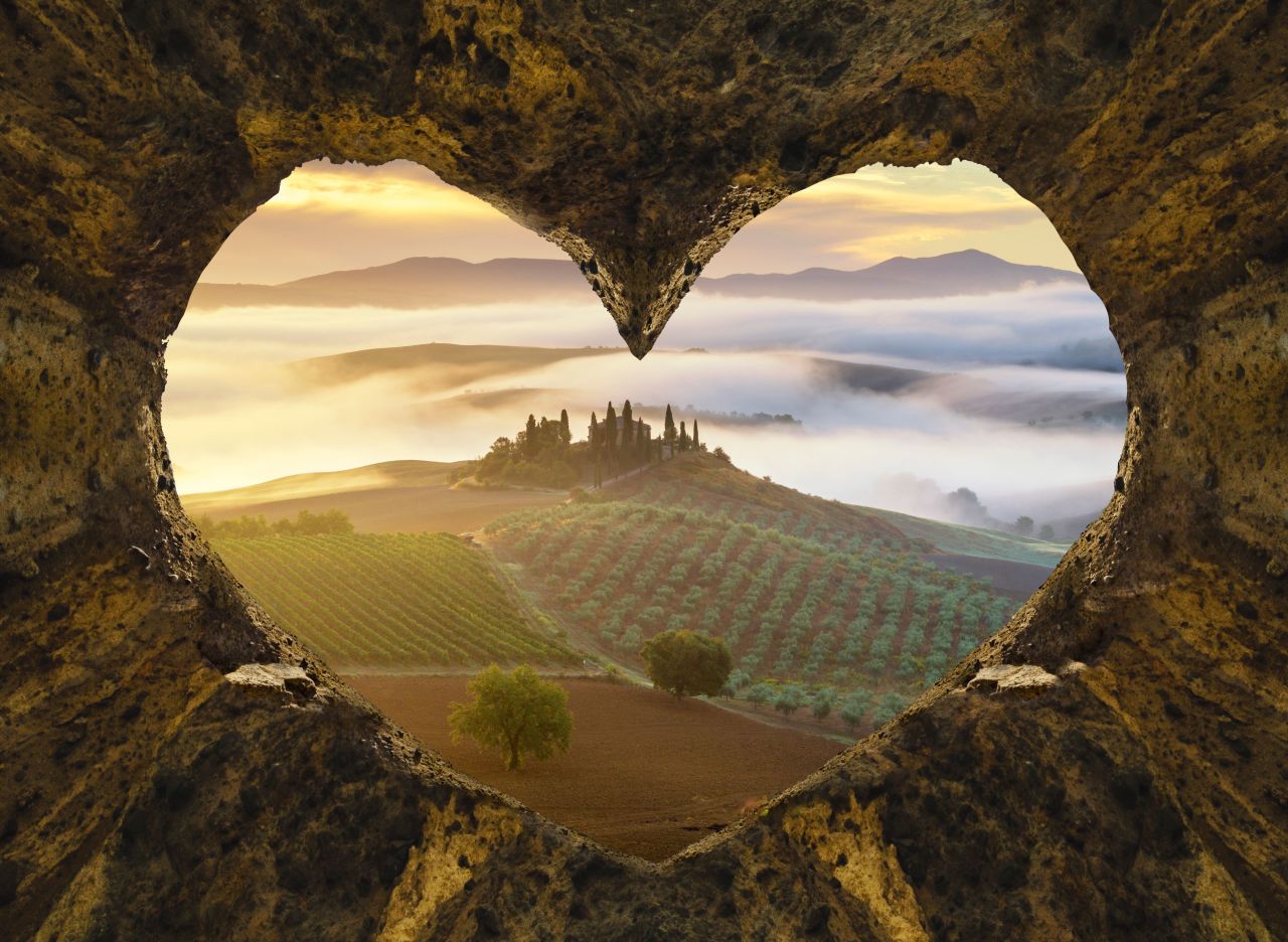 Panorámica de la Toscana al amanecer, vista a través de un corazó