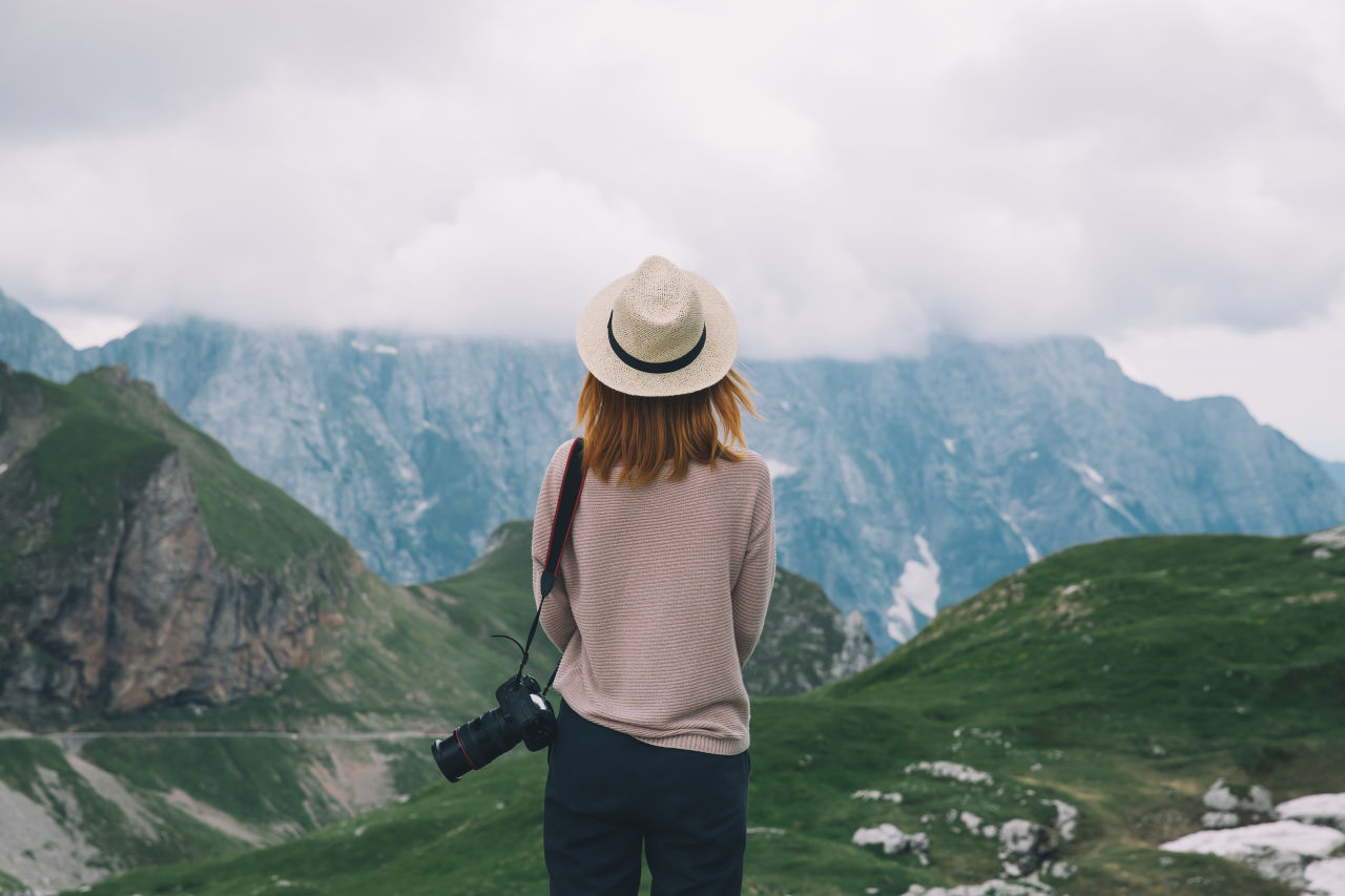 A solo traveller with camera staring into the mountains whilst on holiday