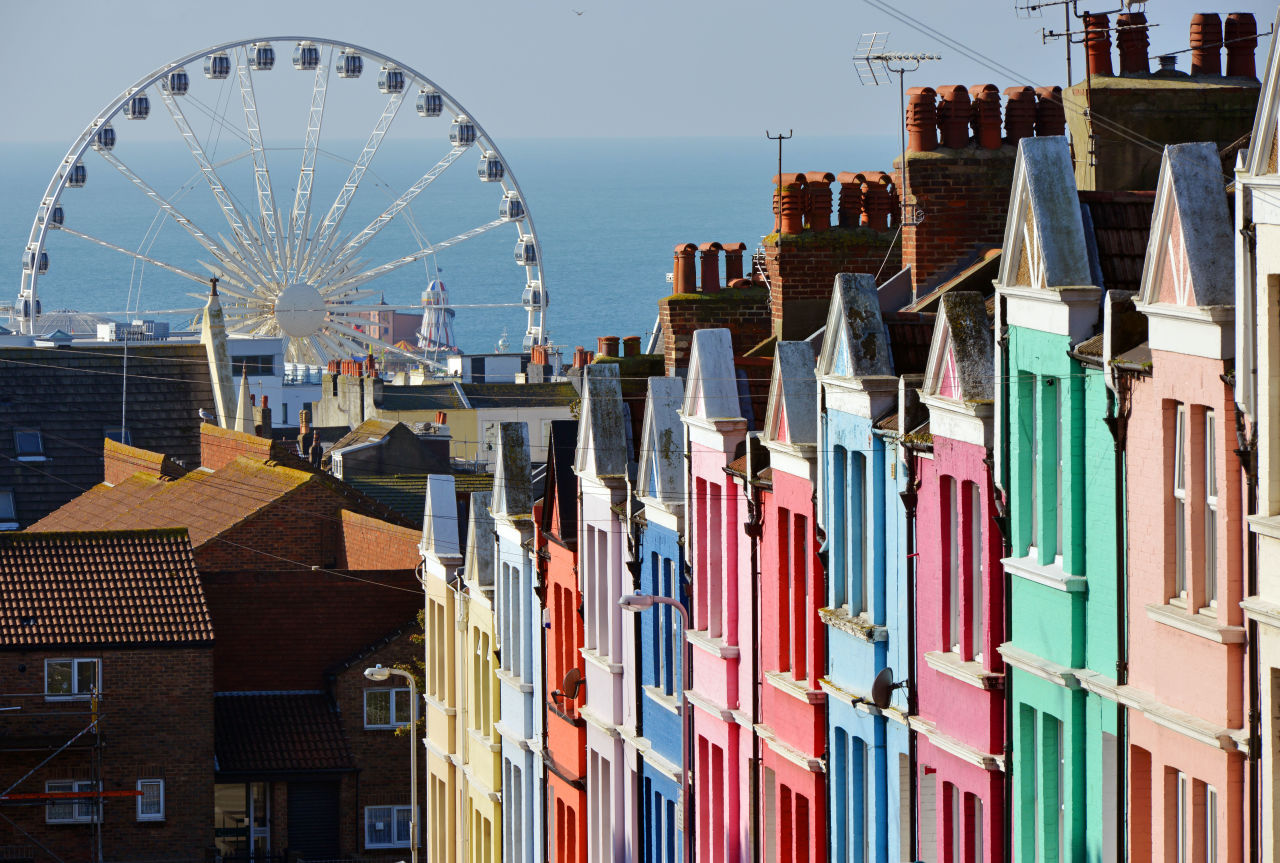 A row of colourful houses in Brighton with a big wheel in the background
