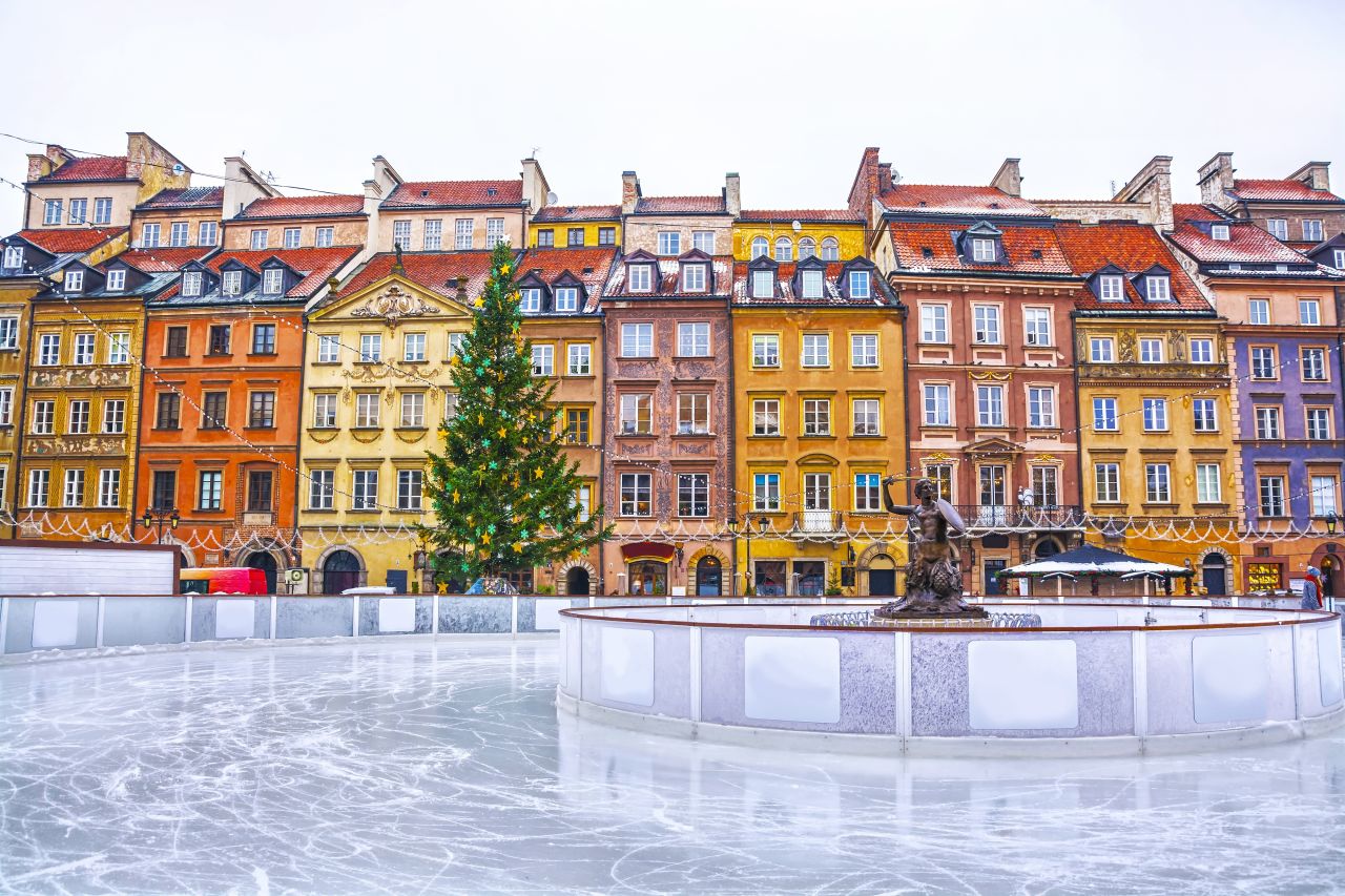 An ice rink in front of a row of colourful houses
