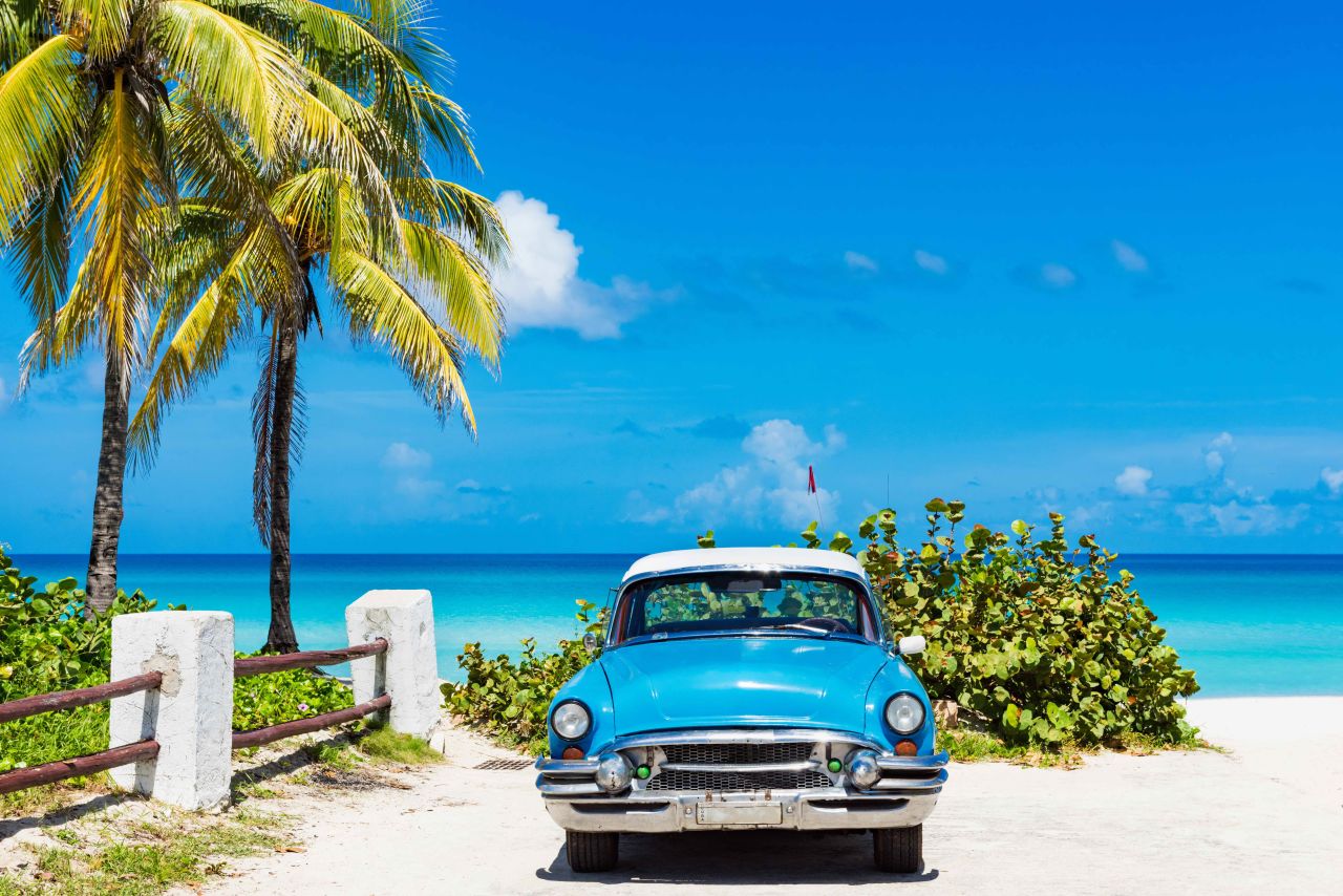 Blauwe oldtimer aan het strand op Cuba