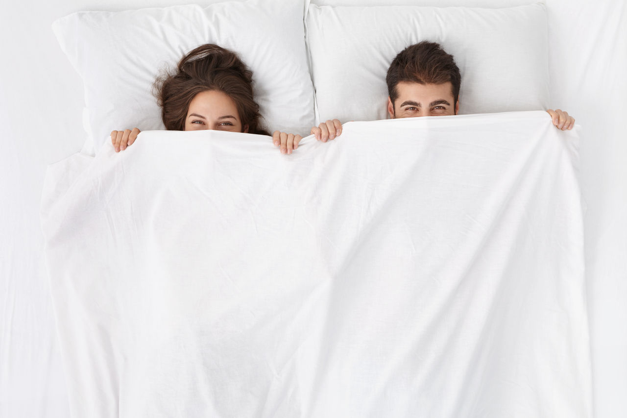 A couple in a bed under the covers