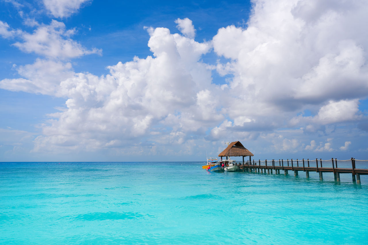 A boardwalk heading into the ocean with a hut at the end