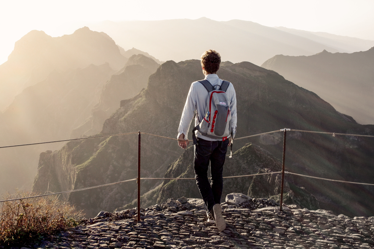 Ein Mann steht am Berggipfel und betrachtet die Landschaft