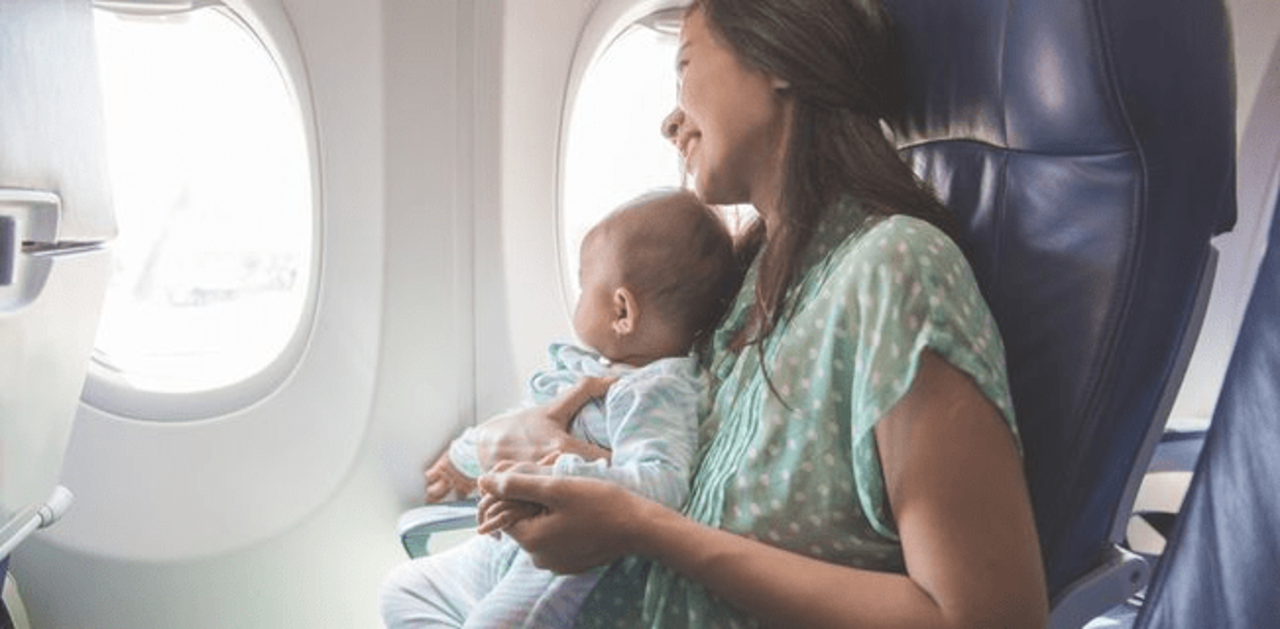 A woman looking out of a plane window with her baby
