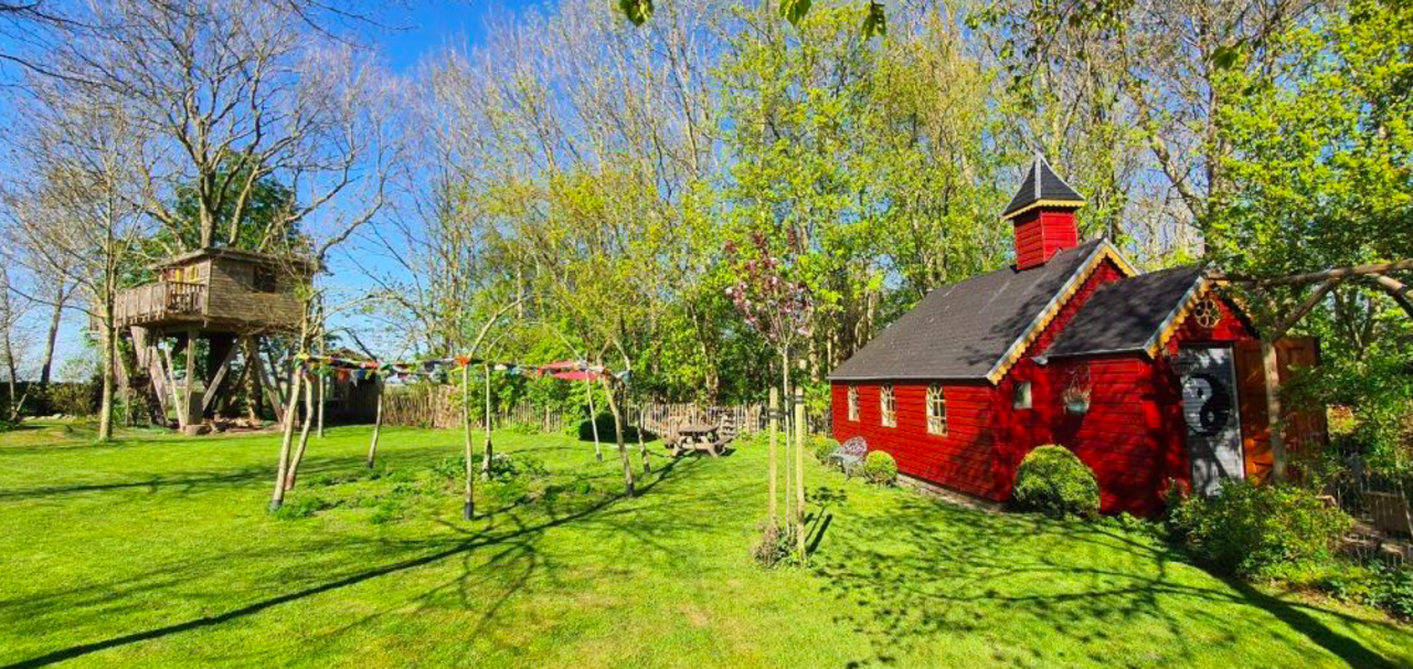 Rood kapelletje van hout in een groene tuin in Friesland