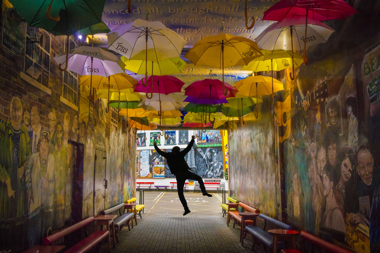 A man jumping with colourful umbrellas