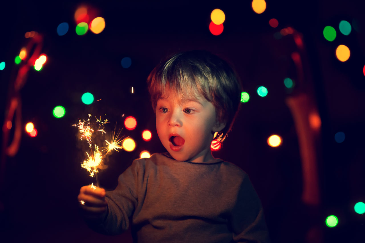 A child holds a lit sparkler at a NYE party