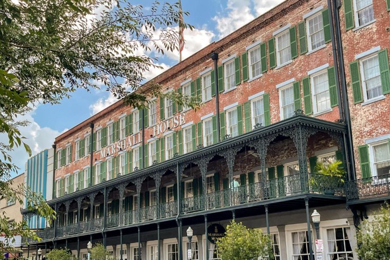 outside of hotel with green shutters and a balcony
