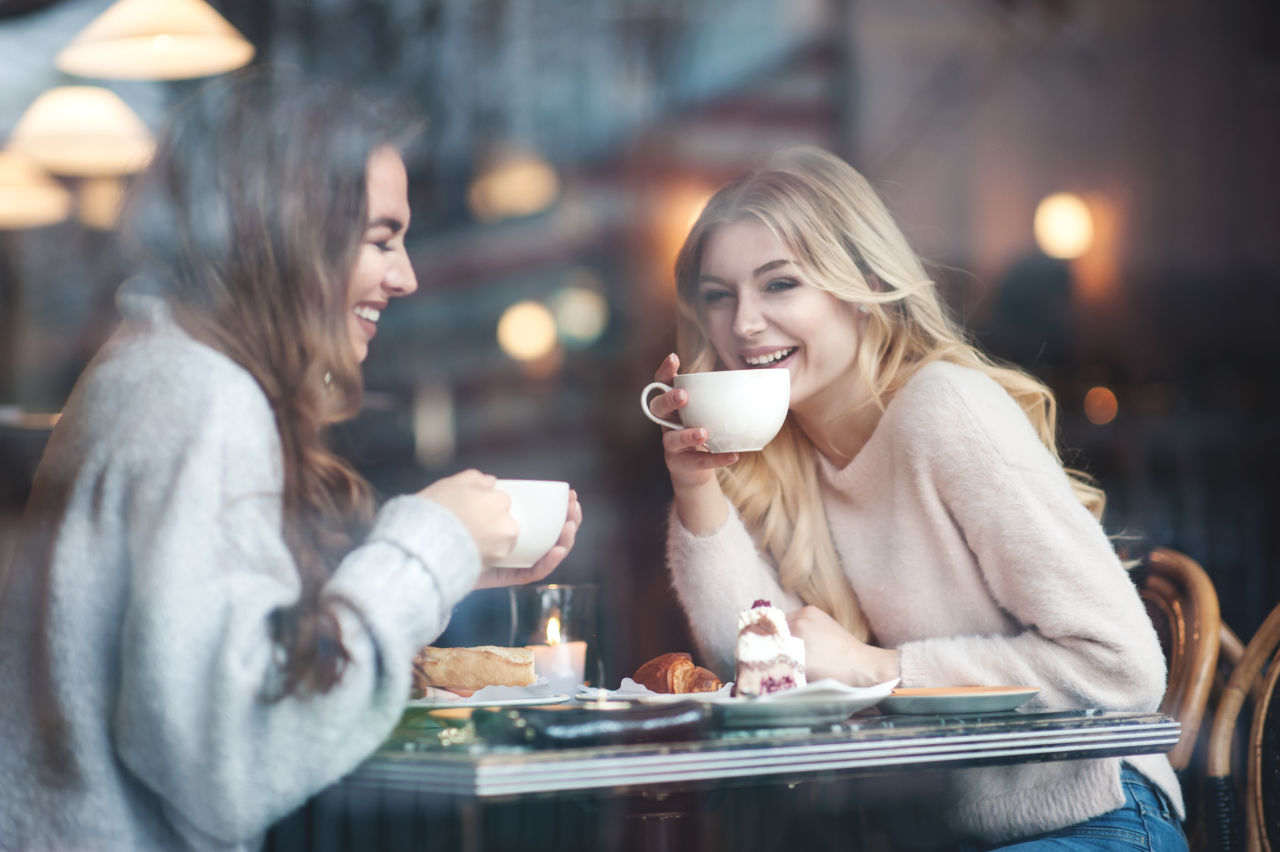 two women drinking coffee in a cafe and laughing