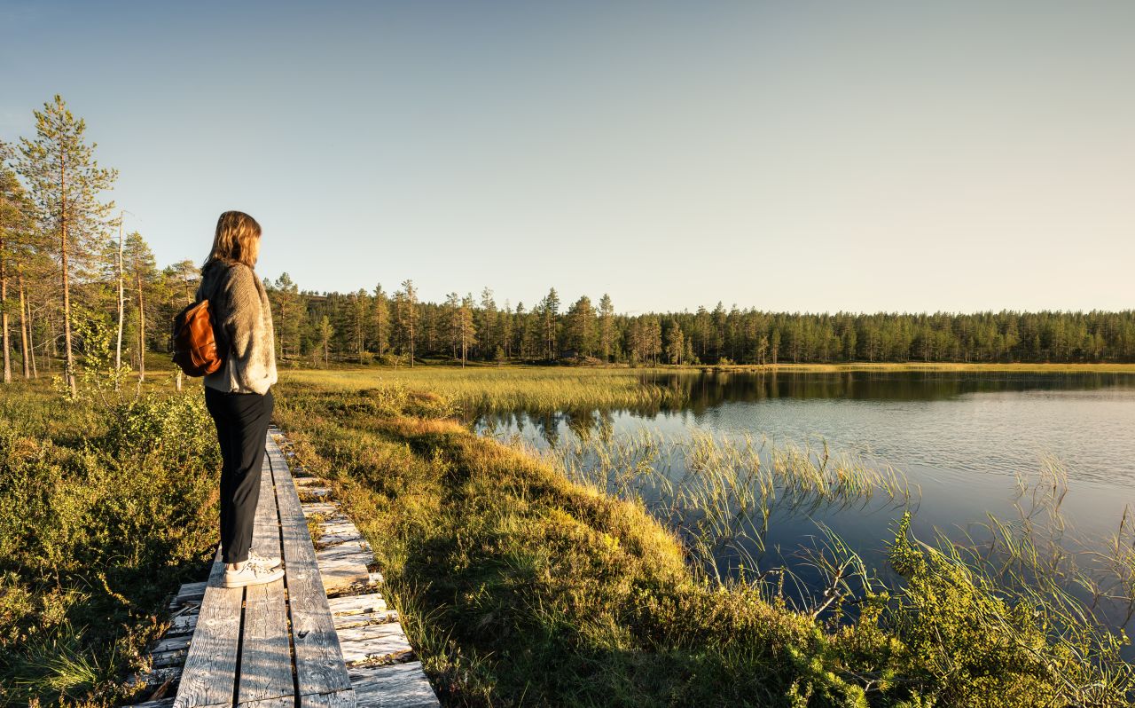 woman standing on the side of a lake and looking towards it