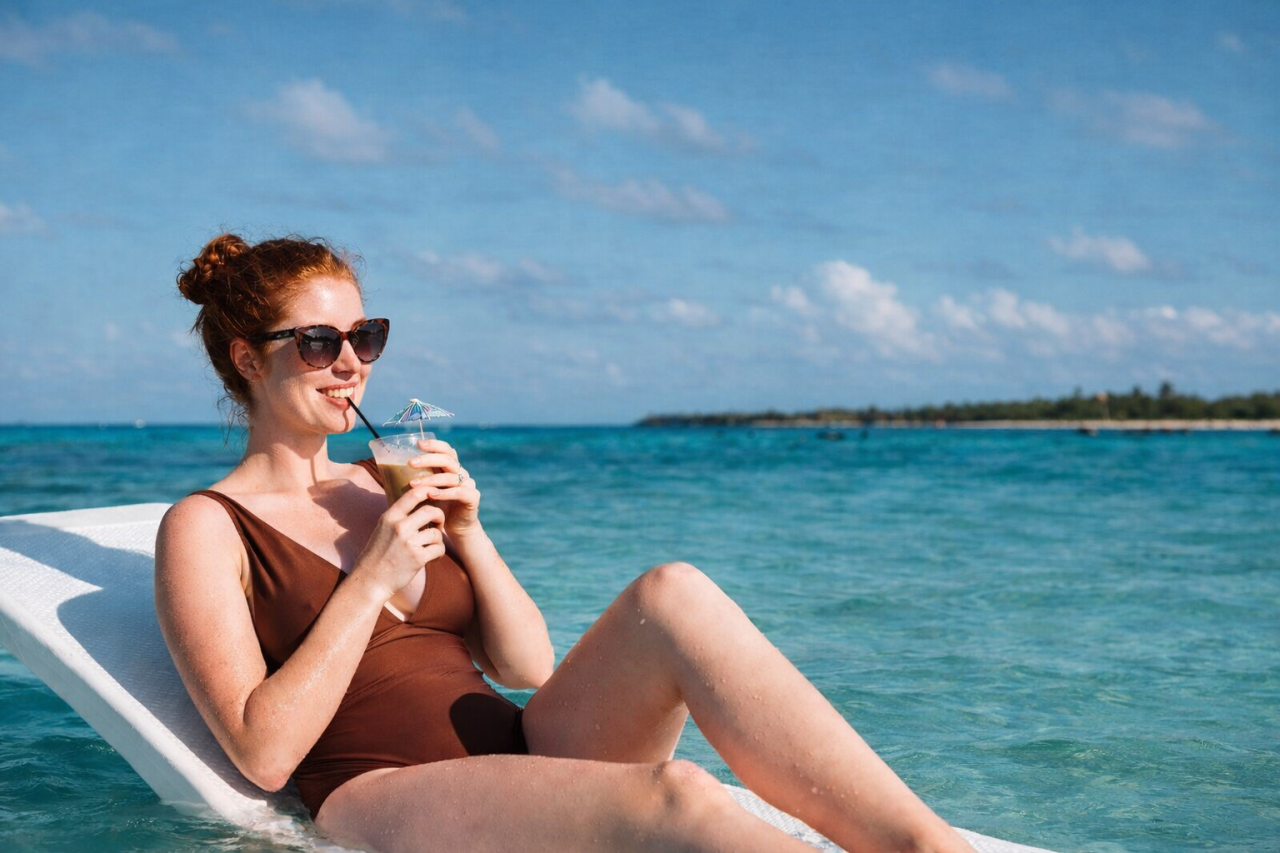 Woman relaxing on a float while sipping from a drink in the Grand Cayman turquoise water relaxation vacation Cayman Islands