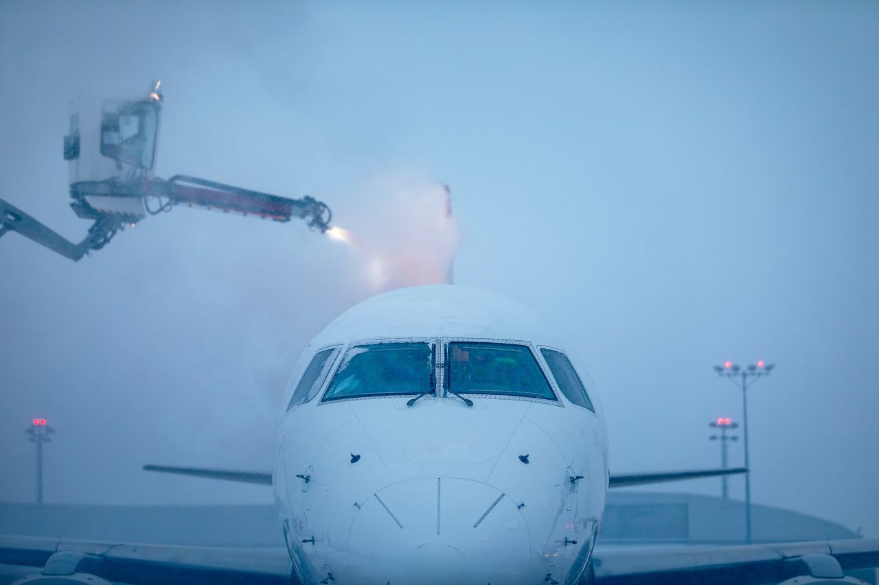 Airplane undergoing de-icing procedure during winter storm at snow-covered airport