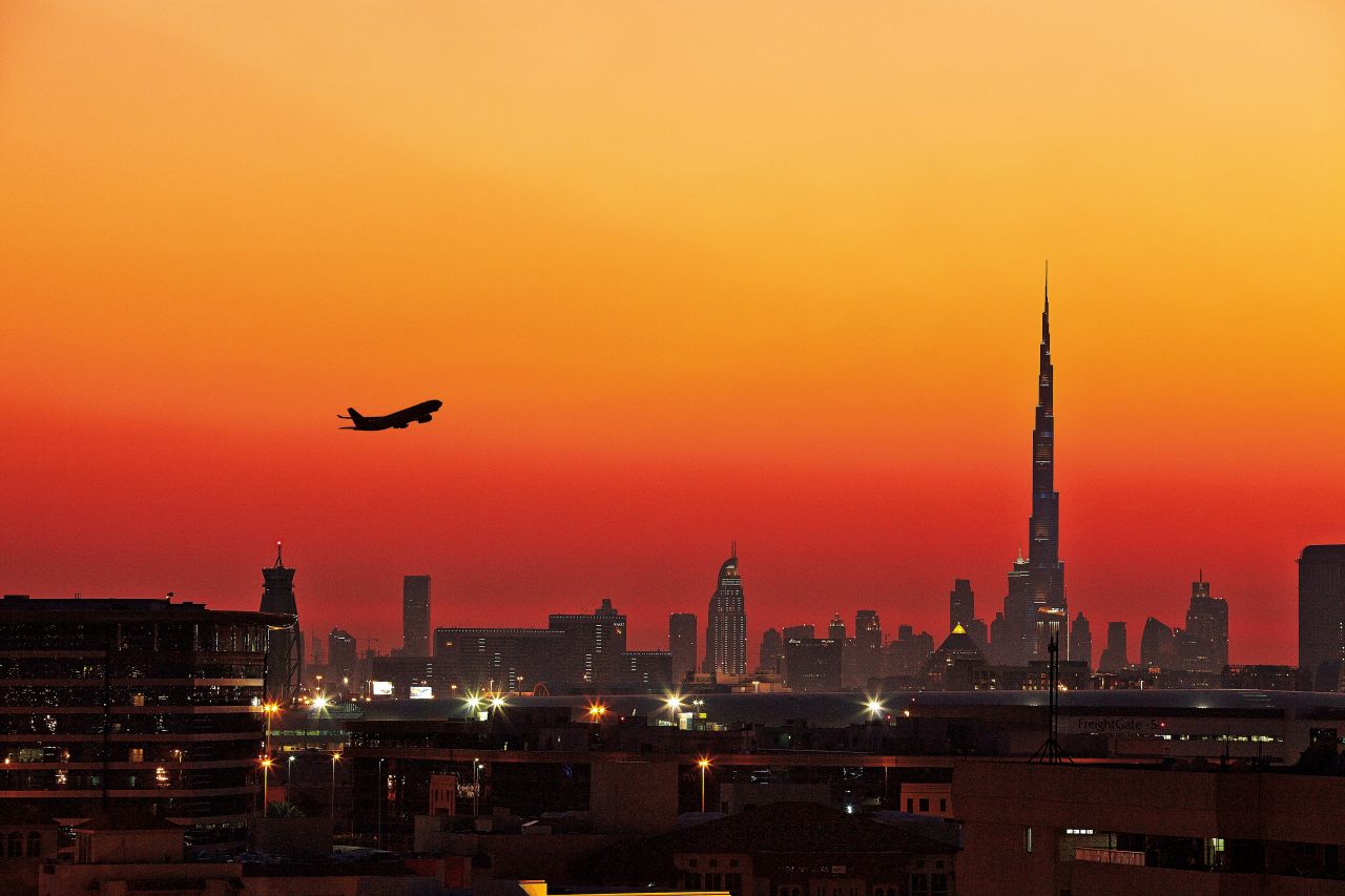 Night city panorama Dubai and airplane taking off