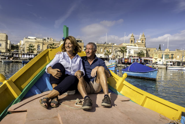 a couple on a colorful boat in Marsaxlokk, Malta