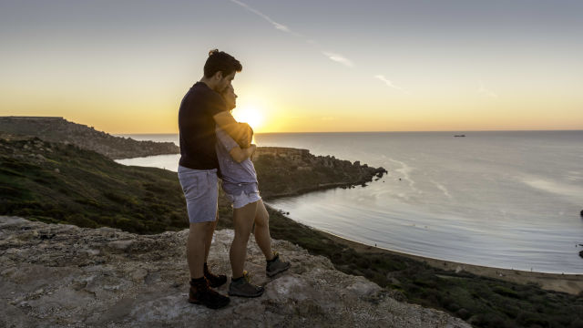 a couple in Malta watching the sunset and embracing