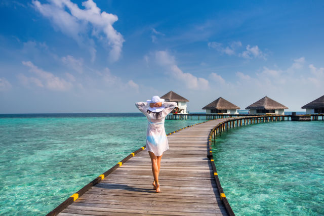 Vrouw die op een loopbrug bij de Malediven loopt.