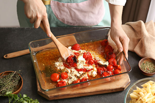 woman stirring feta into tomatoes and pasta