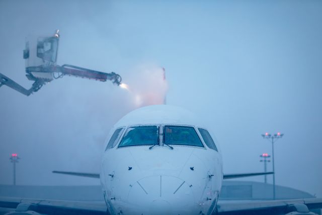 Airplane undergoing de-icing procedure during winter storm at snow-covered airport