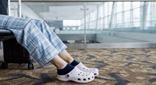 woman wearing crocs and pajamas while waiting at the airport