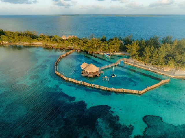 Aerial view of Thatch Caye private island resort in Belize with overwater bungalows and turquoise Caribbean water