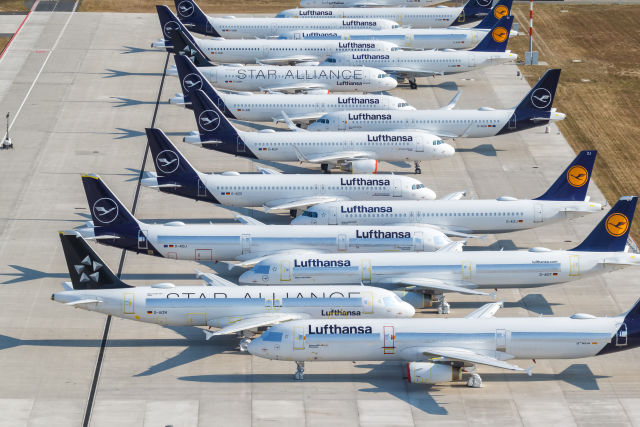 Vliegtuigen van Lufthansa op een rij bij het vliegveld: Lufthansa schrapt 20.000 vluchten zomer 2026.