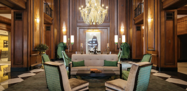 Restored 1920s lobby at The Read House Hotel in Chattanooga with wood-paneled walls, green velvet chairs, patterned floors, and a dramatic chandelier.