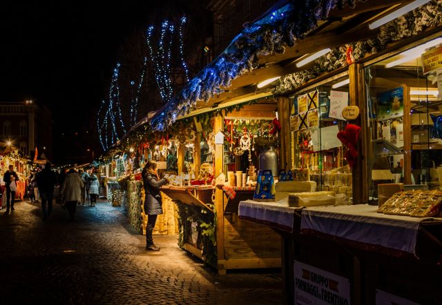 Christmas market stalls glowing with festive lights at night in Trento, Italy