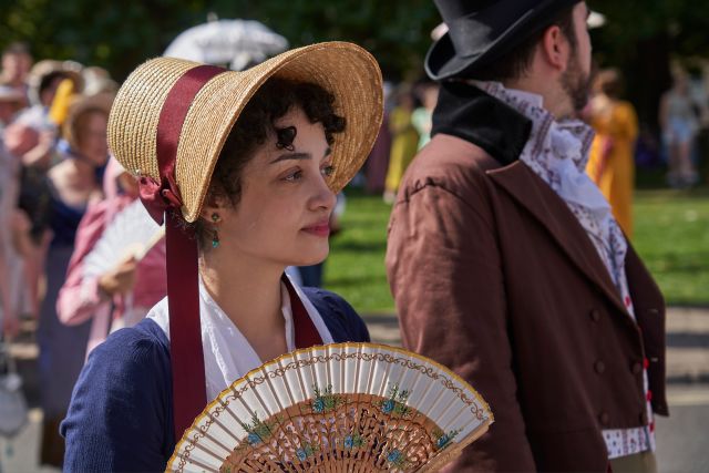 Woman in Regency dress and bonnet holding a fan at the Jane Austen Festival in Bath, England