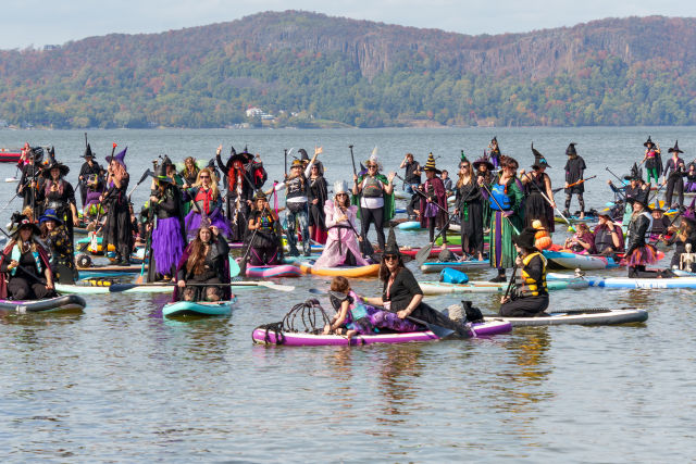 Costumed witches paddleboarding on the Hudson River during the SUP Witches Festival in Sleepy Hollow, New York