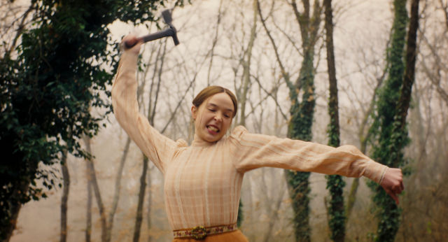 Ella Beatty as Lizzie Borden swings a hatchet overhead in a misty, ivy-covered forest in Netflix's Monster: The Lizzie Borden Story